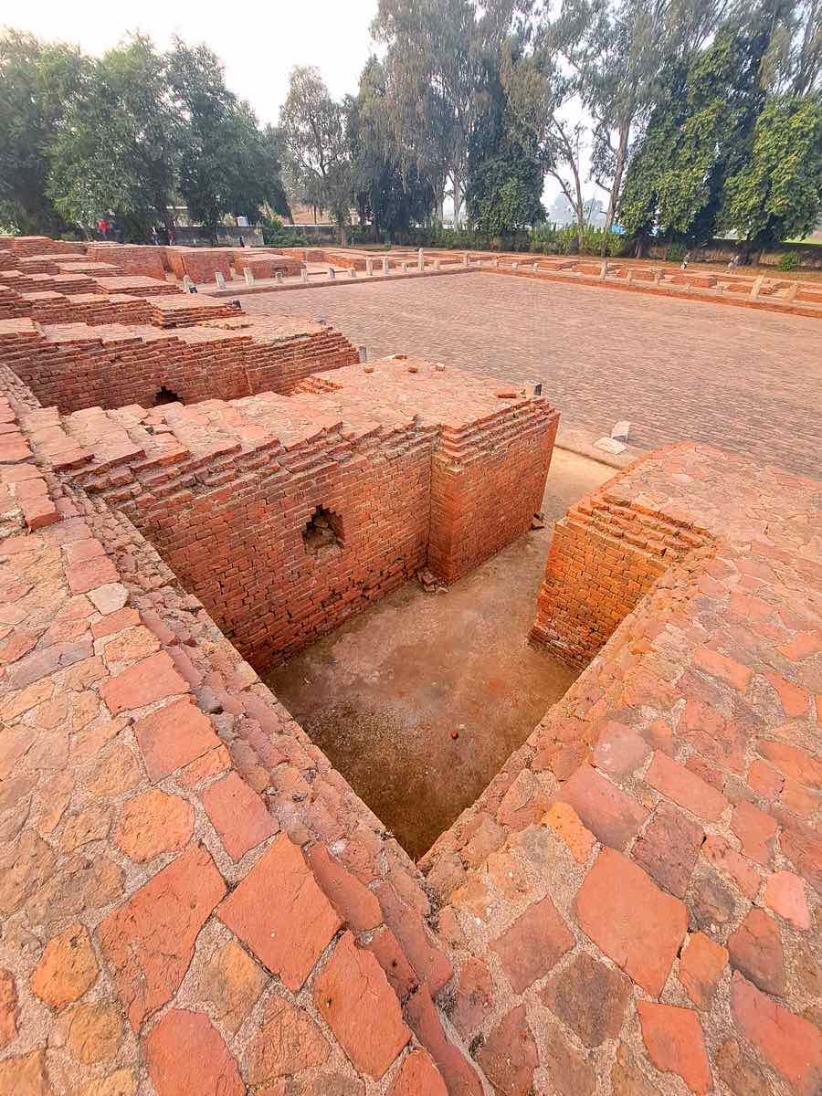 Inside an excavated monastery court at Nalanda: cell doorways around the open courtyard